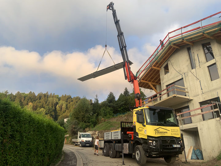 Grue du camion amenant les toles sur le toit